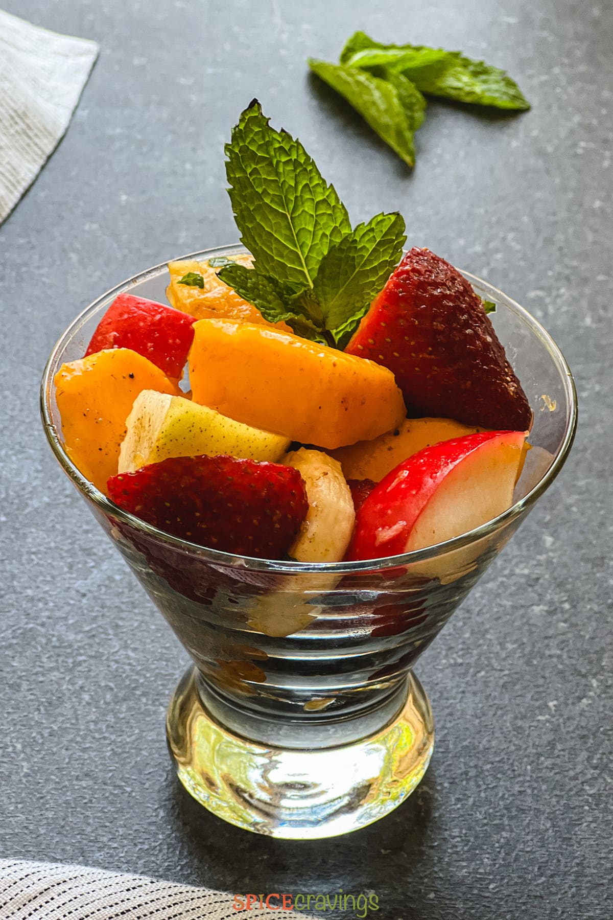 Fruit salad in martini glass garnished with mint leaves