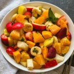 Fruit salad in white bowl seasoned with spices and mint