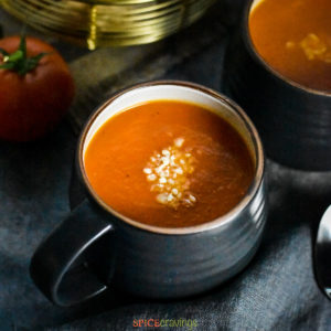 Cup of tomato and red pepper soup with grated parmesan cheese