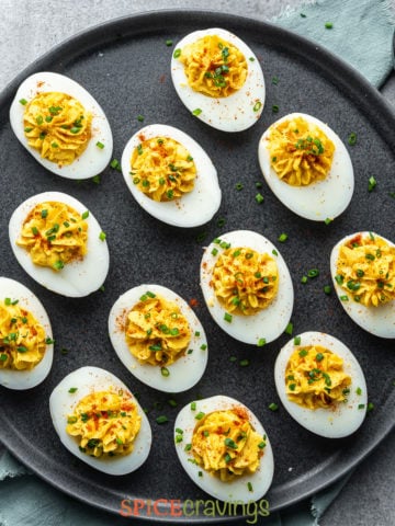 easy spiced deviled eggs arranged on black platter