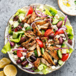 best chicken greek salad in large white serving bowl with dressing on the side