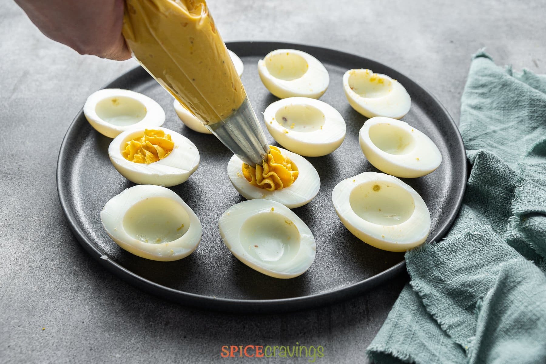 filling egg whites with spicy deviled egg filling from piping bag