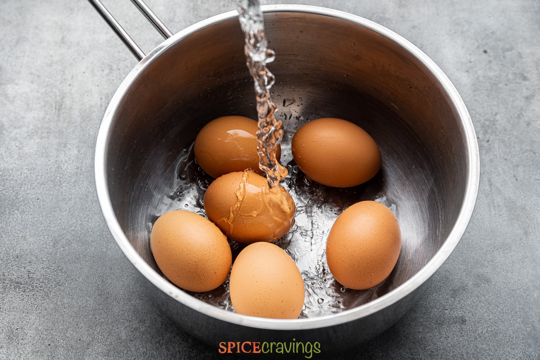 pouring water over eggs in saucepan
