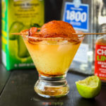 Glass with spicy margarita topped with dried mango with chili