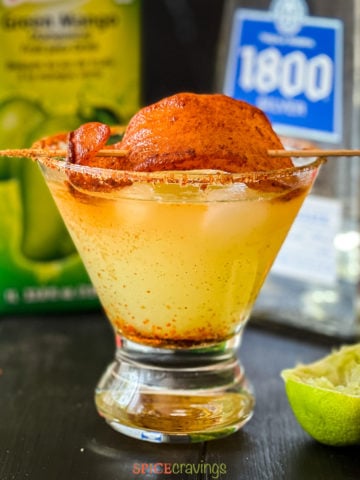 Glass with spicy margarita topped with dried mango with chili