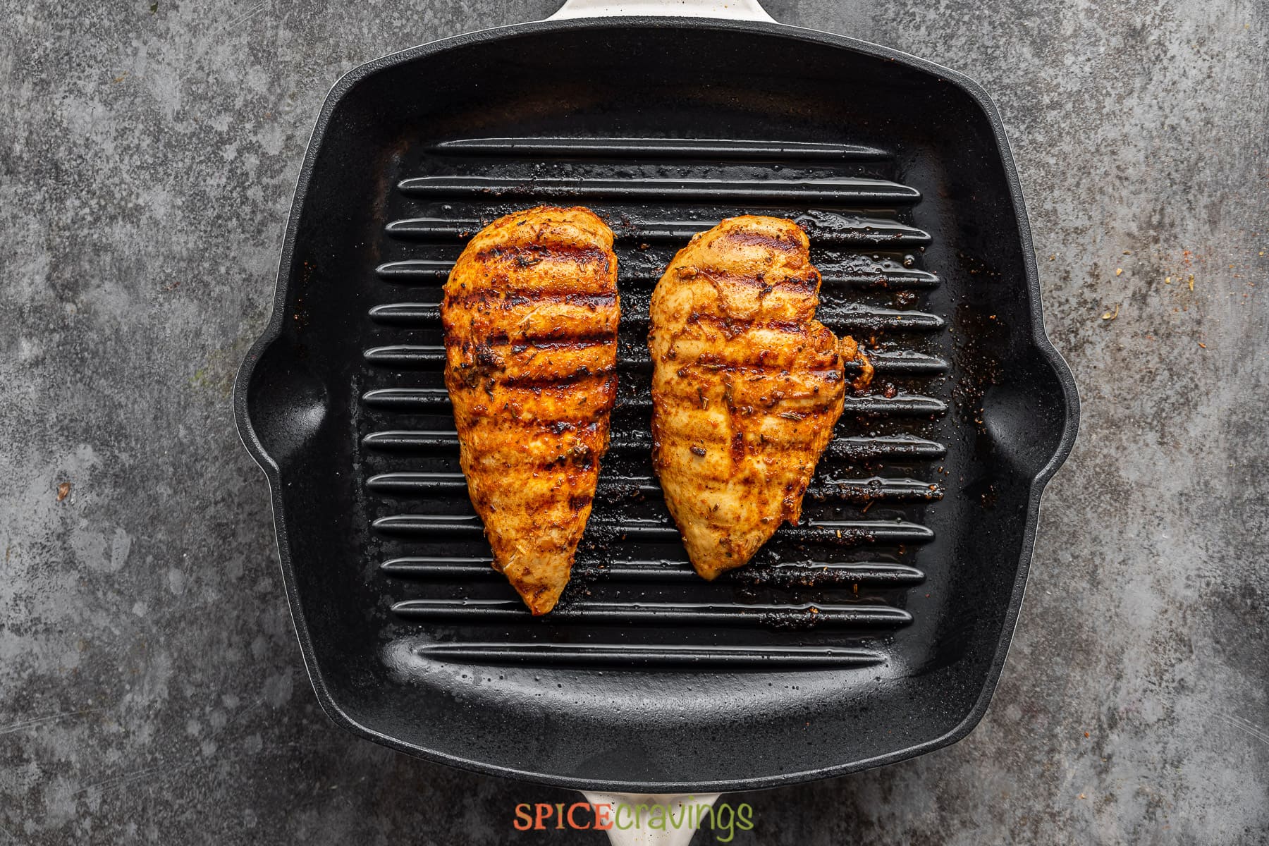 two grilled cajun chicken breasts on grill pan