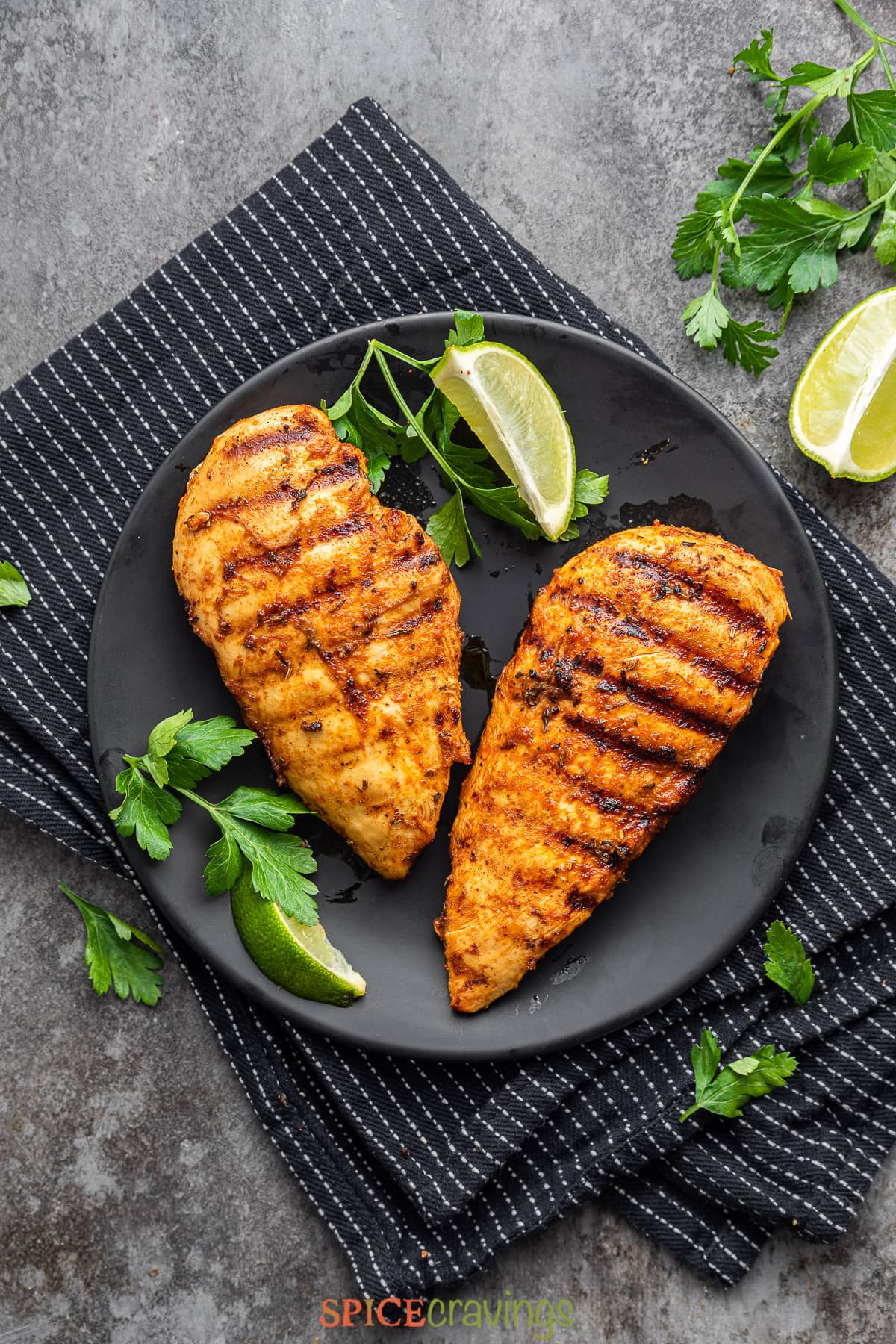 two cajun chicken breasts on black plate with lime wedge and cilantro