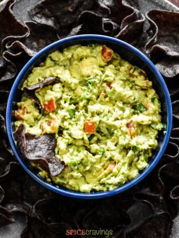 Bowl with guacamole surrounded with blue corn chips