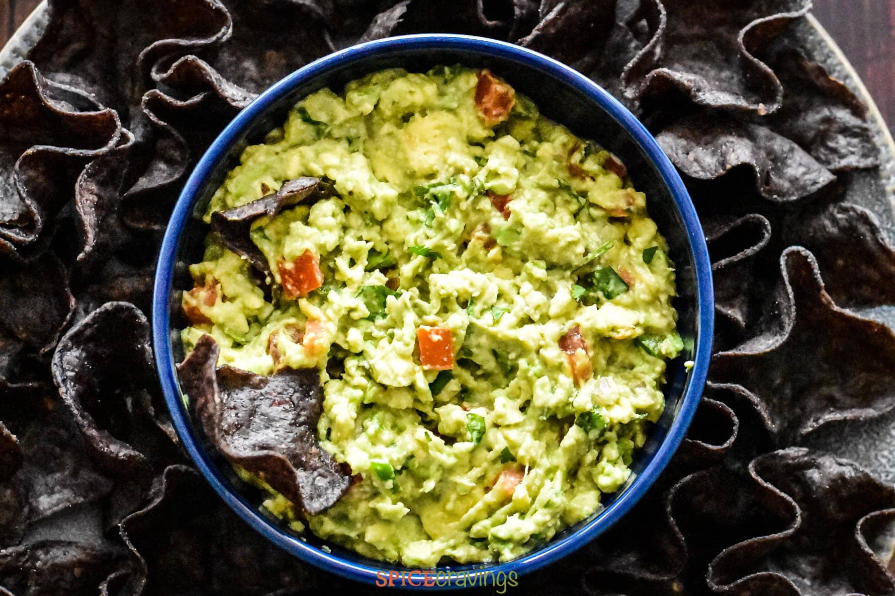 Guacamole with tomatoes and cilantro in blue bowl