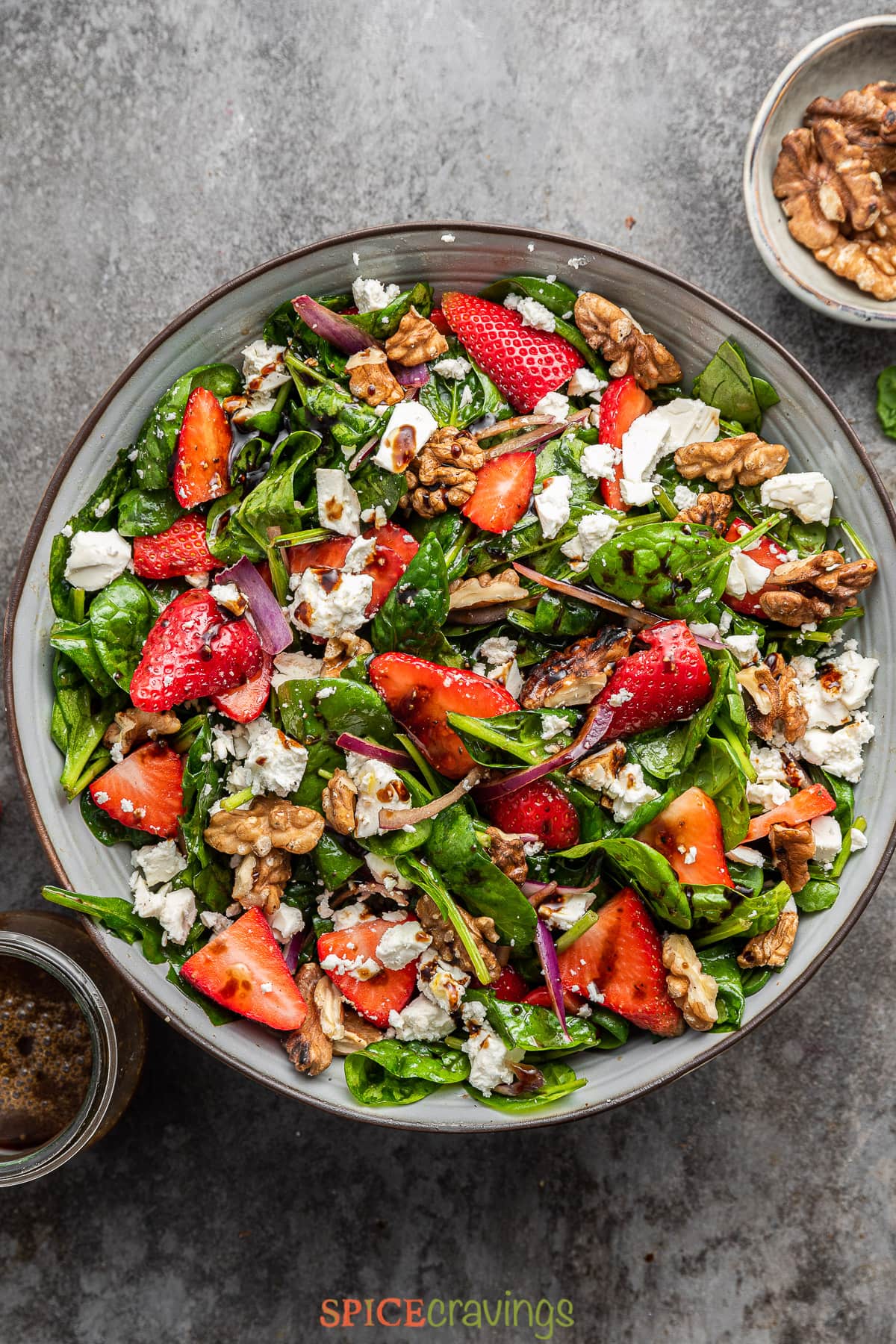 strawberry spinach salad recipe topped with feta cheese and nuts in large bowl