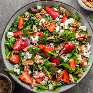 strawberry and spinach salad with feta cheese and nuts in large bowl