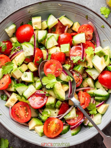 easy cucumber tomato avocado salad recipe in large bowl with serving spoon