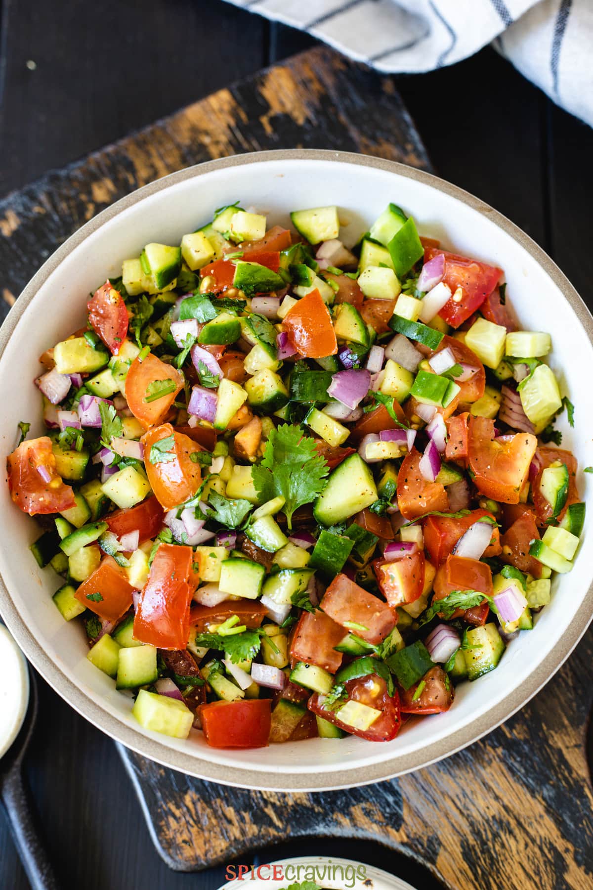 chopped salad made of cucumber, tomato and onion in white bowl