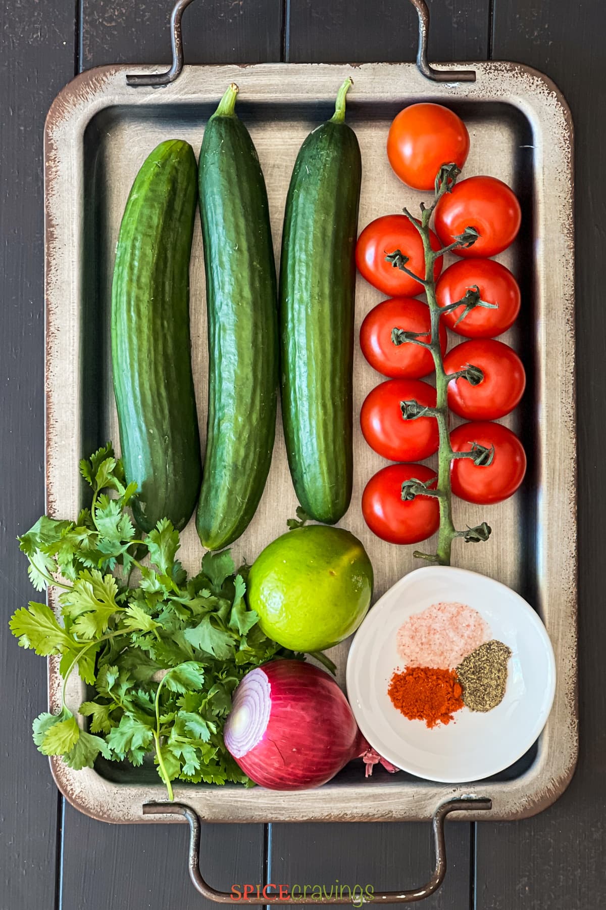 Cucumber, tomato, cilantro, lime, onion and spices on metal tray