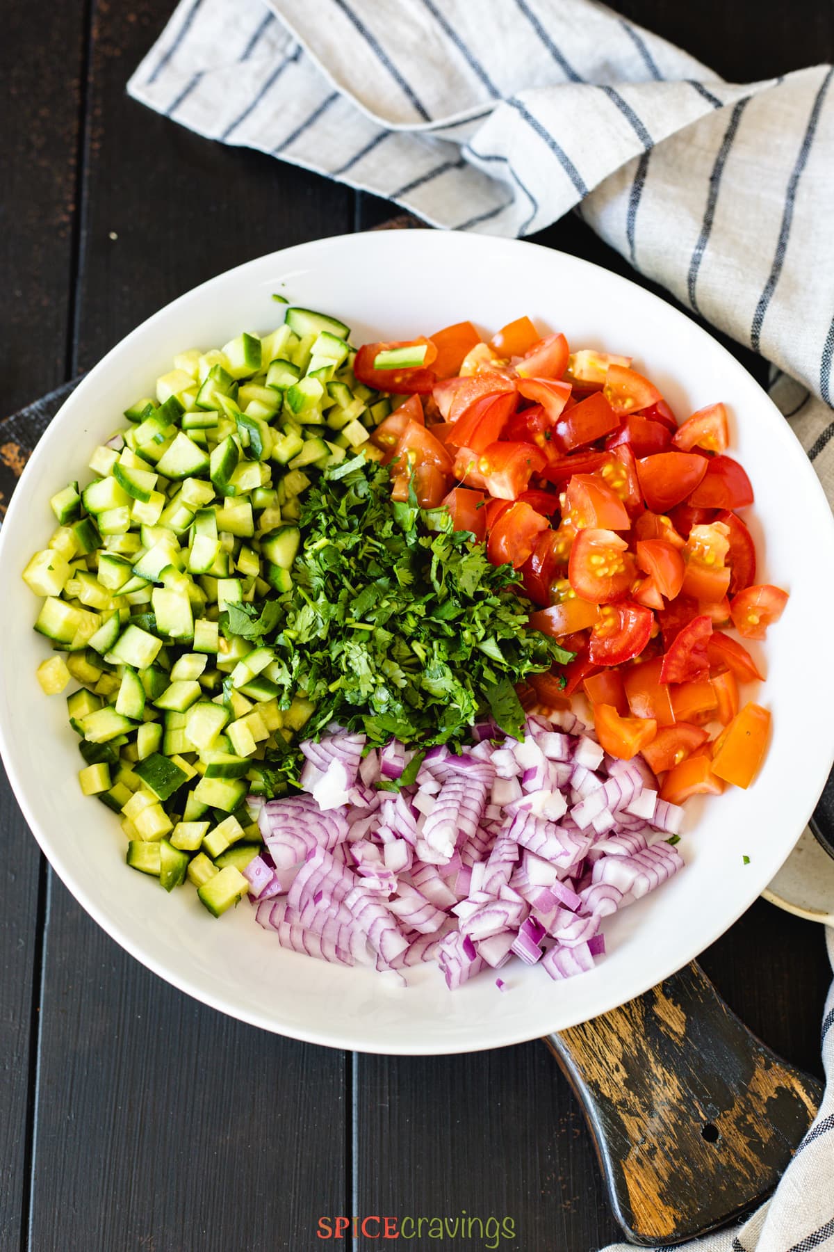 chopped salad made of cucumber, tomato, cilantro and onion in white bowl