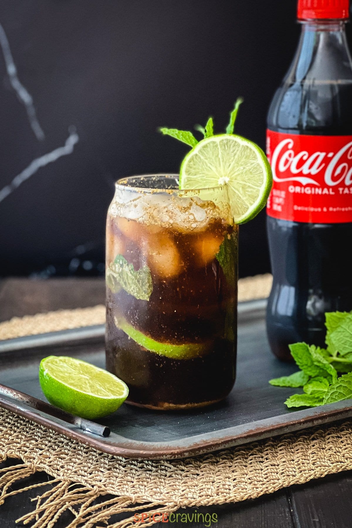 Glass of coke with lime slice next to a bottle of coca-cola