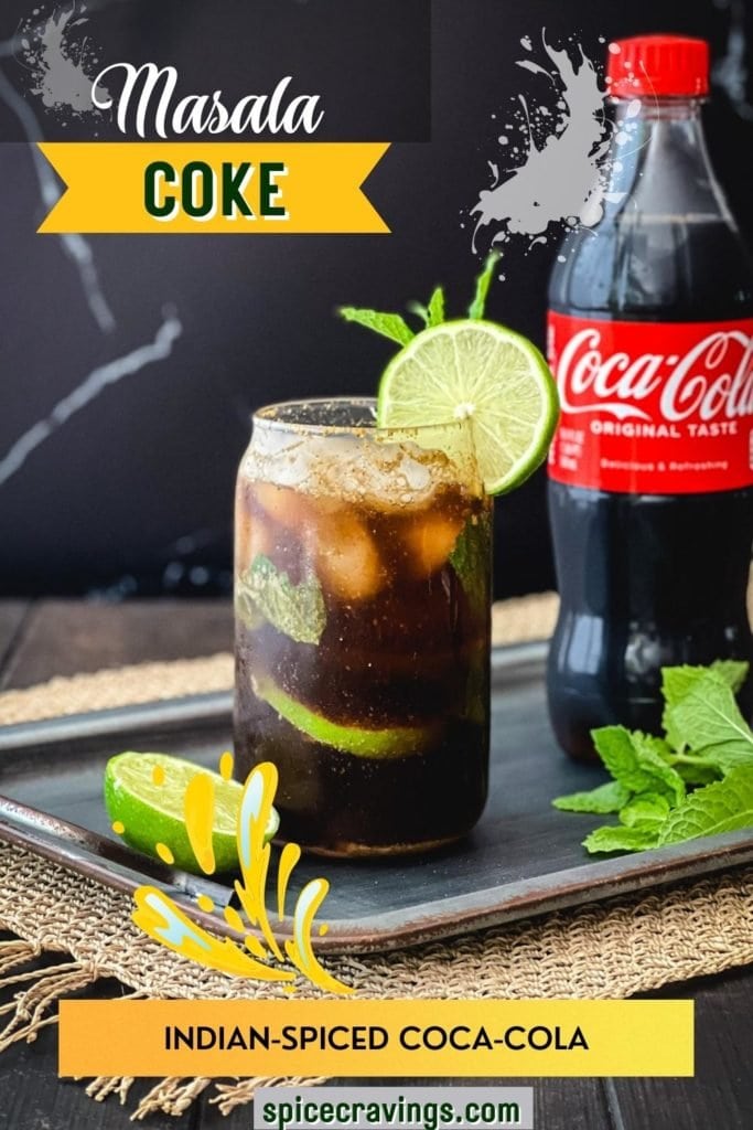 Glass of coke with lime and mint next to a bottle of coca-cola