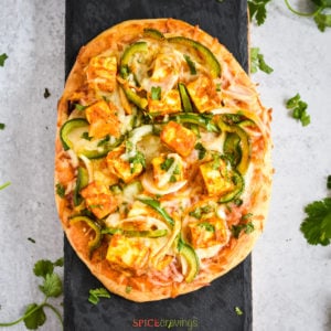 Naan pizza with paneer and peppers on black slate