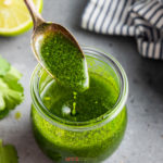 spoonful of cilantro lime vinaigrette drizzling into glass jar full of dressing