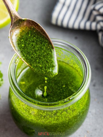spoonful of cilantro lime vinaigrette drizzling into glass jar full of dressing
