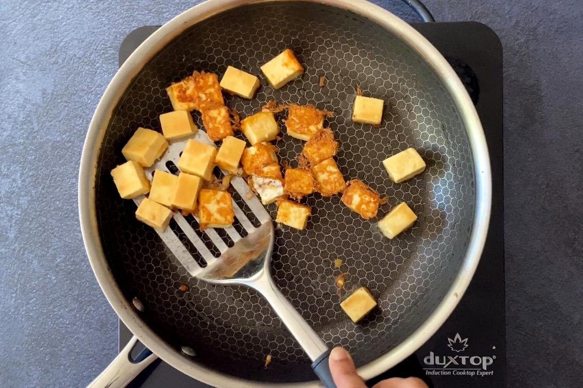 Pan frying paneer cubes in skillet to brown them