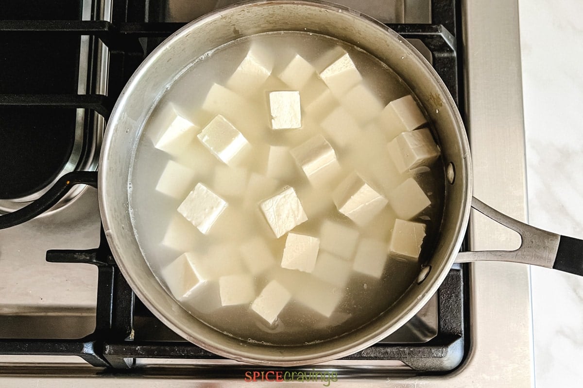 paneer cubes in boiling water in saucepan
