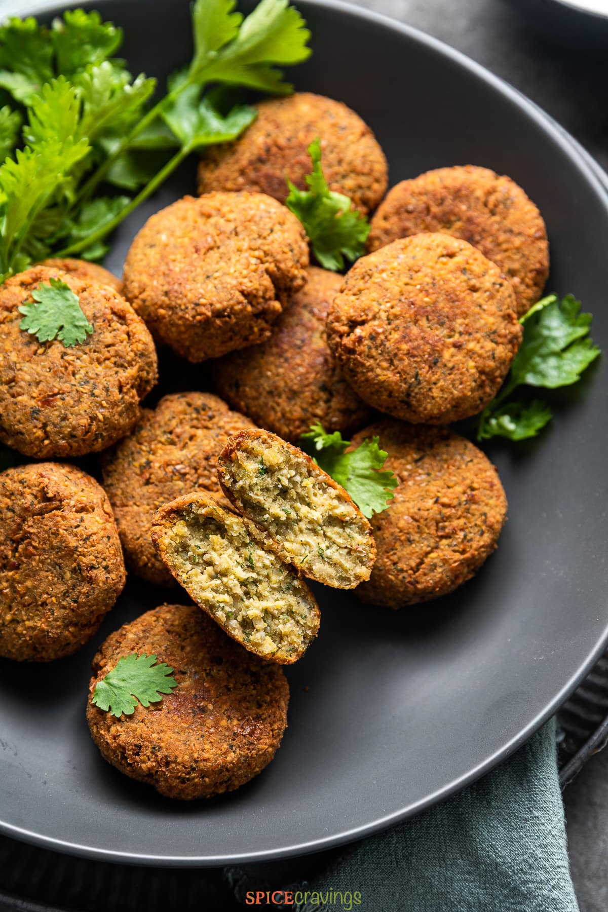 pile of homemade falafel on a black plate with one split open