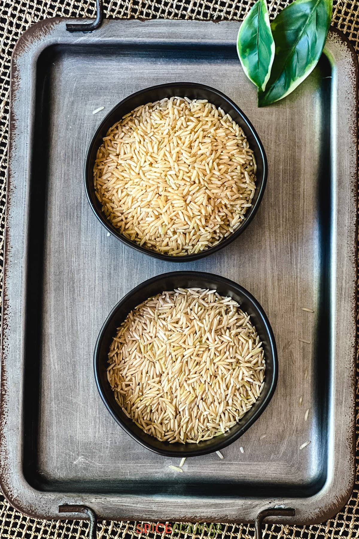 brown basmati rice and jasmine rice in two separate black bowls on serving platter