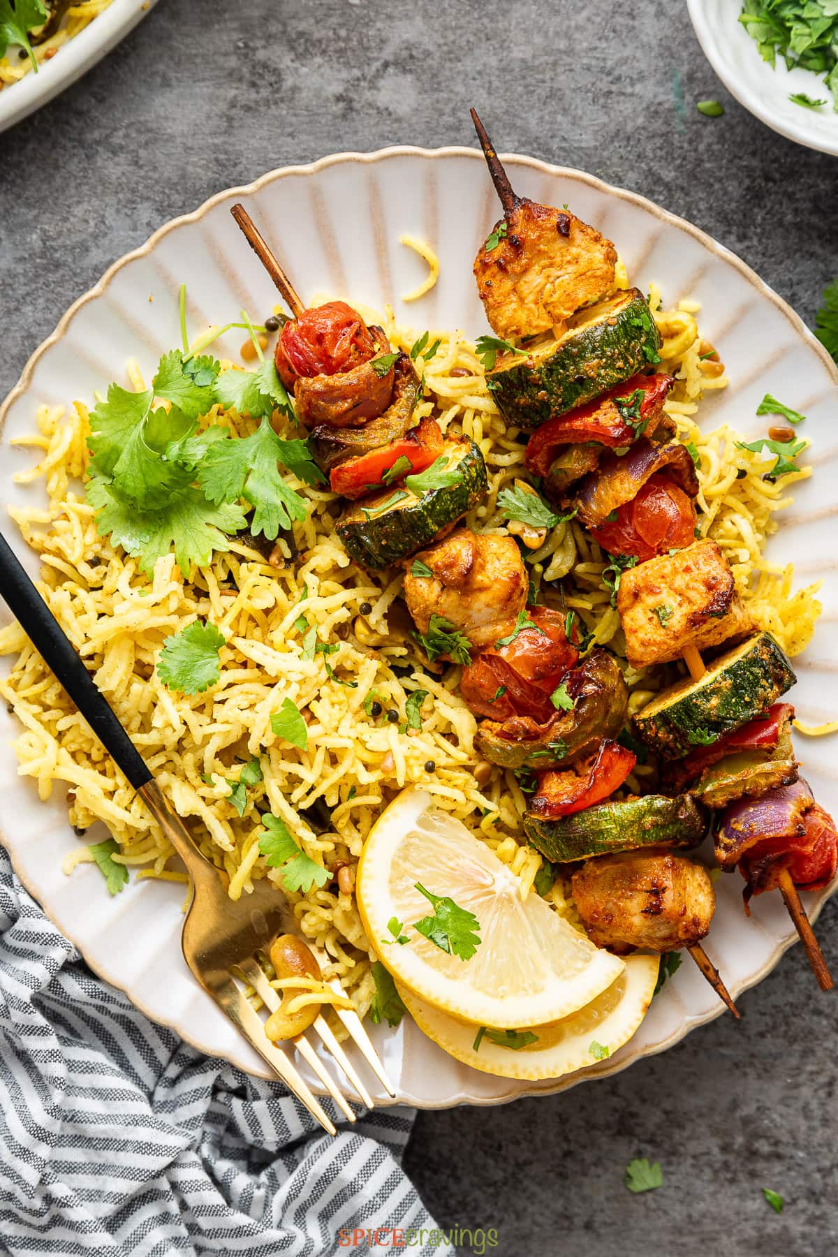 Two shish kebab skewers on a plate of yellow rice