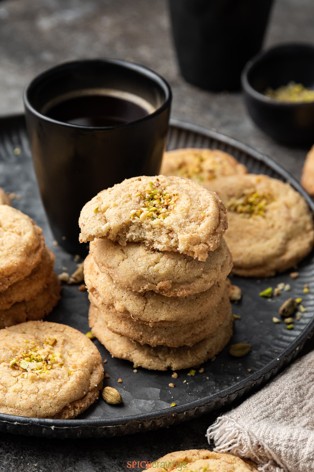 stack of Indian biscuit cookies on black slate with mug of coffee