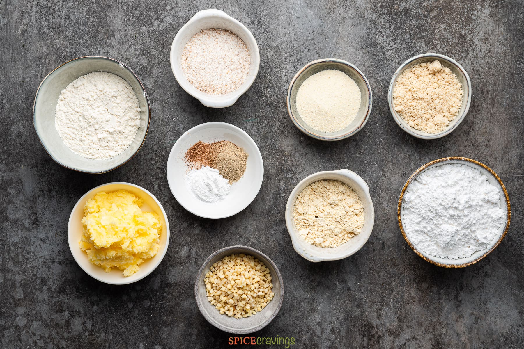 all purpose flour, whole wheat flour, besan, almond flour, semolina, sugar,  cardamom, nutmeg, baking powder, ghee, milk in bowls