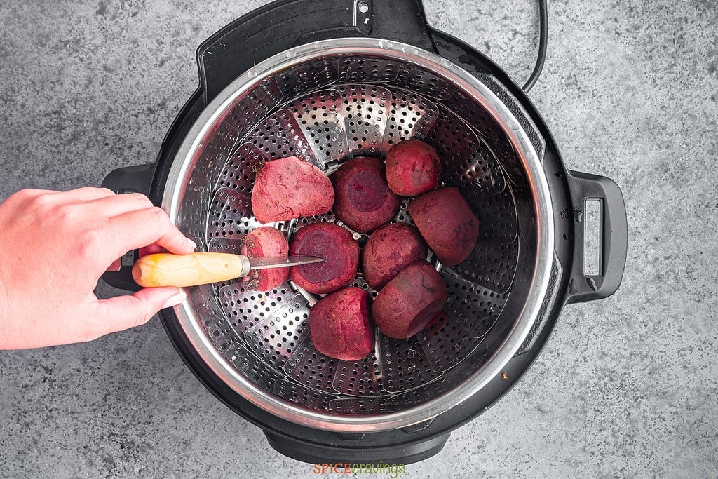 hand piercing knife into beet in Instant Pot