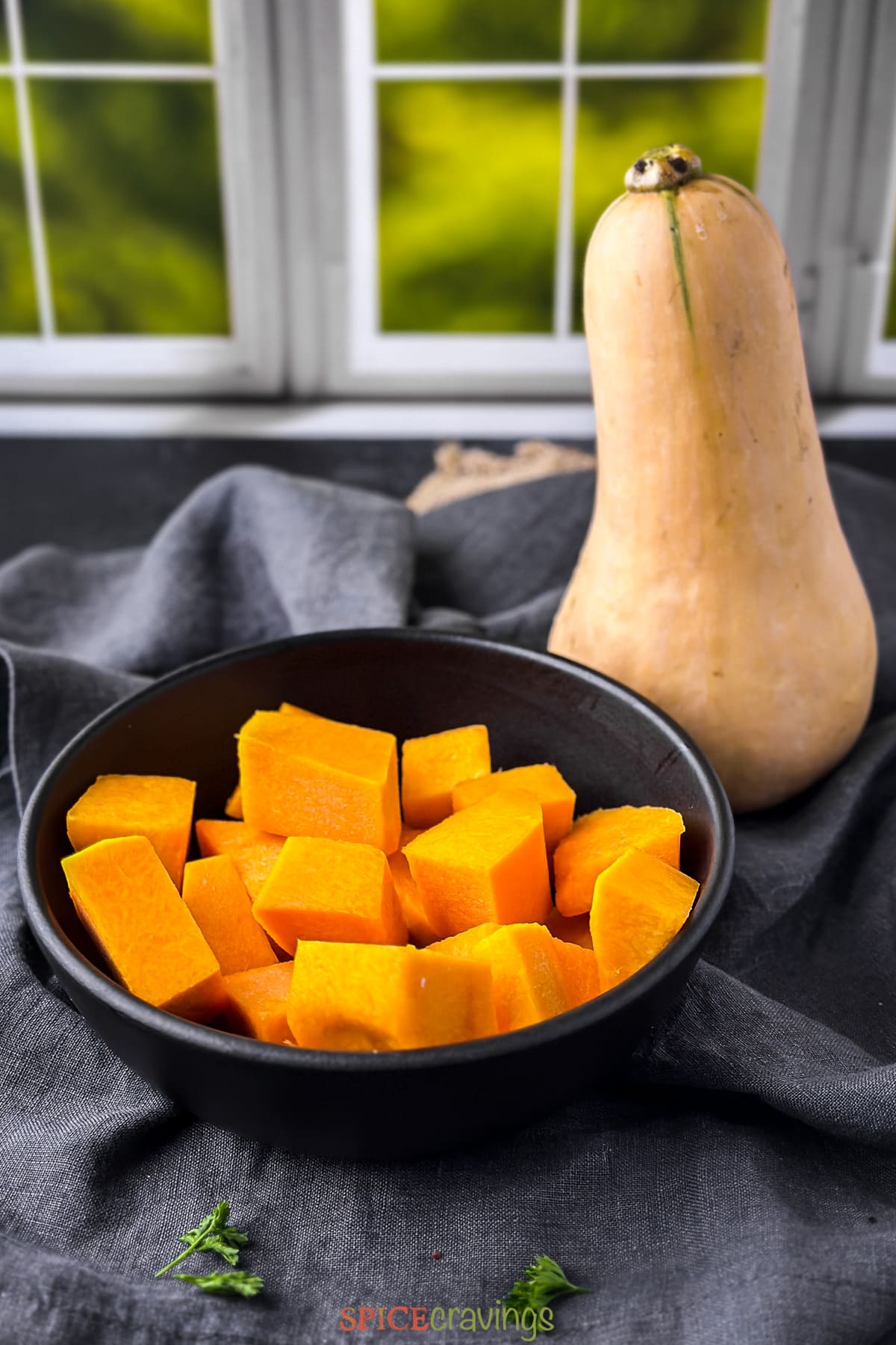 Bowl of cubes butternut squash along with a whole squash
