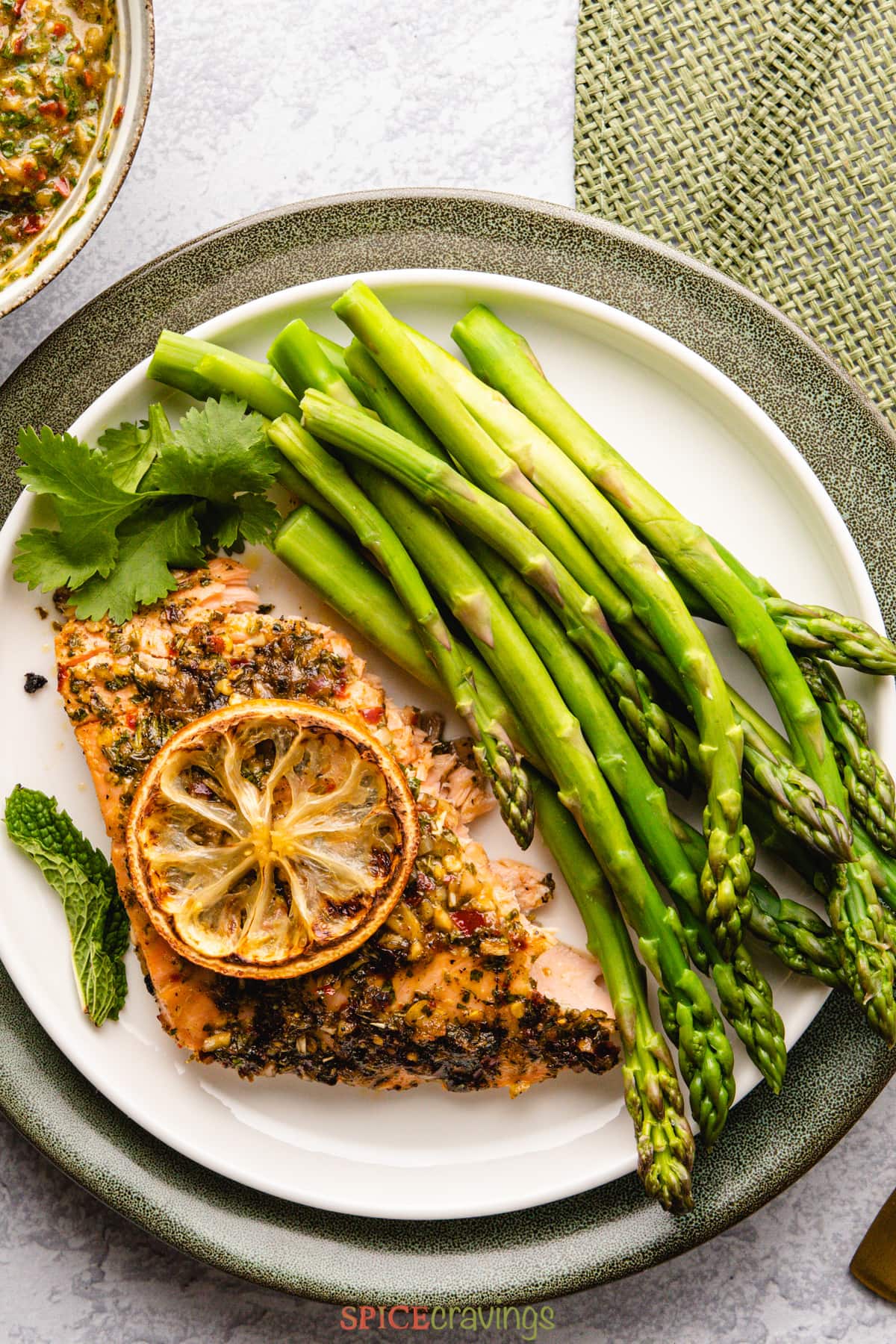 flaky piece of chimichurri salmon with asparagus on white plate
