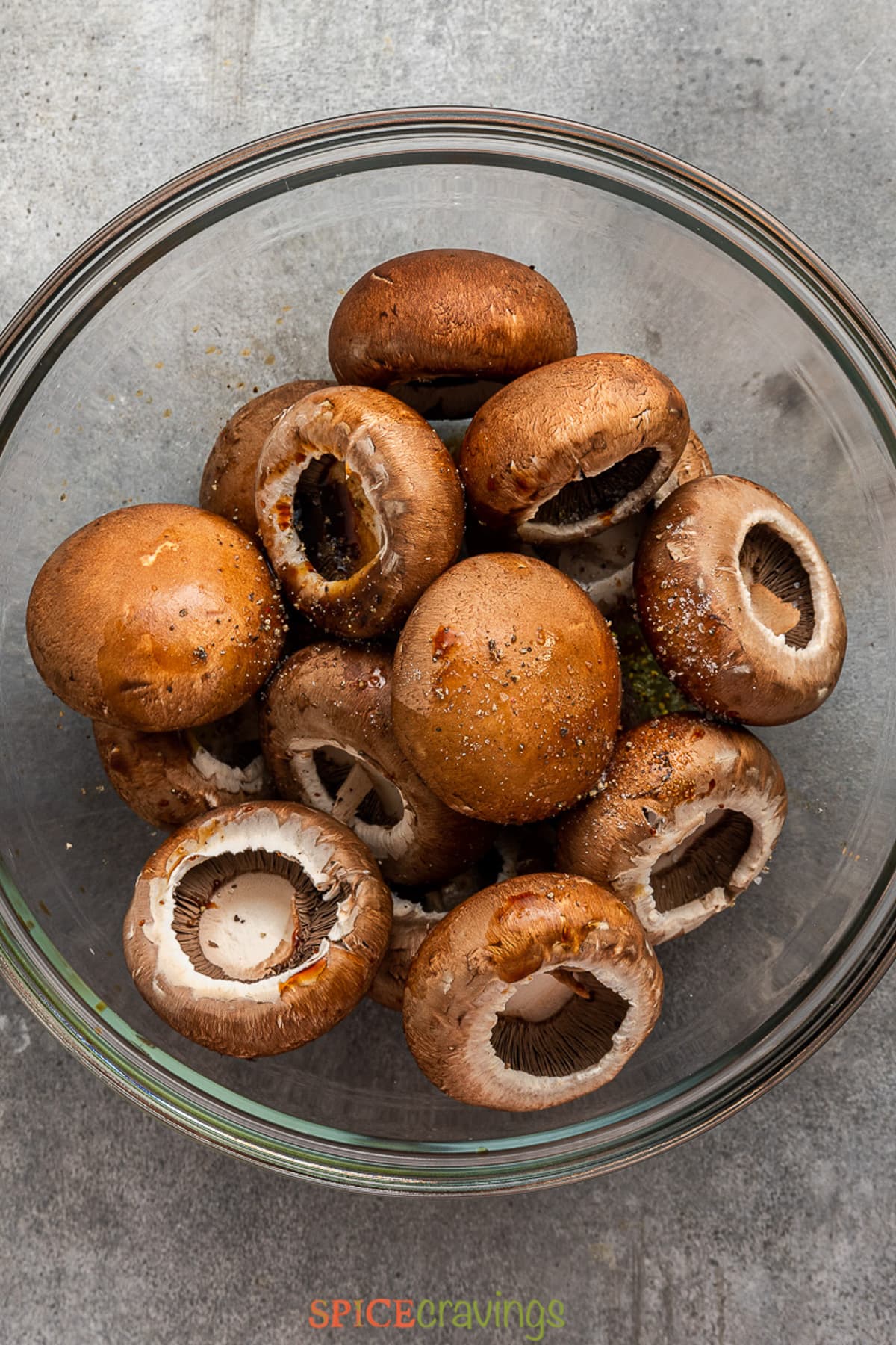 stemmed and clean mushrooms in glass bowl seasoned with salt and pepper.