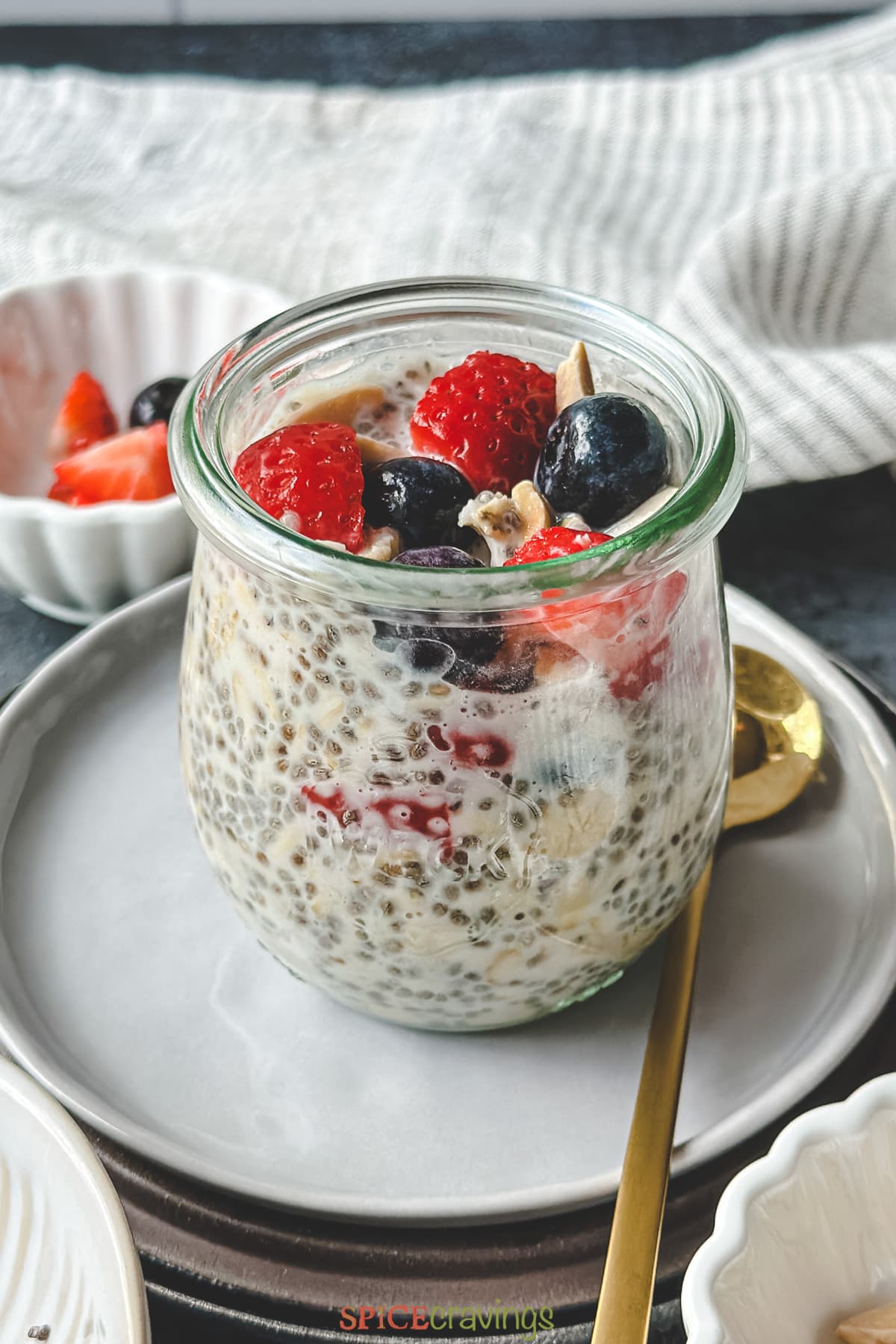 overnight oats with chia seeds in glass jar topped with berries and nuts
