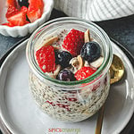 overnight oats with chia seeds in glass jar topped with berries and nuts