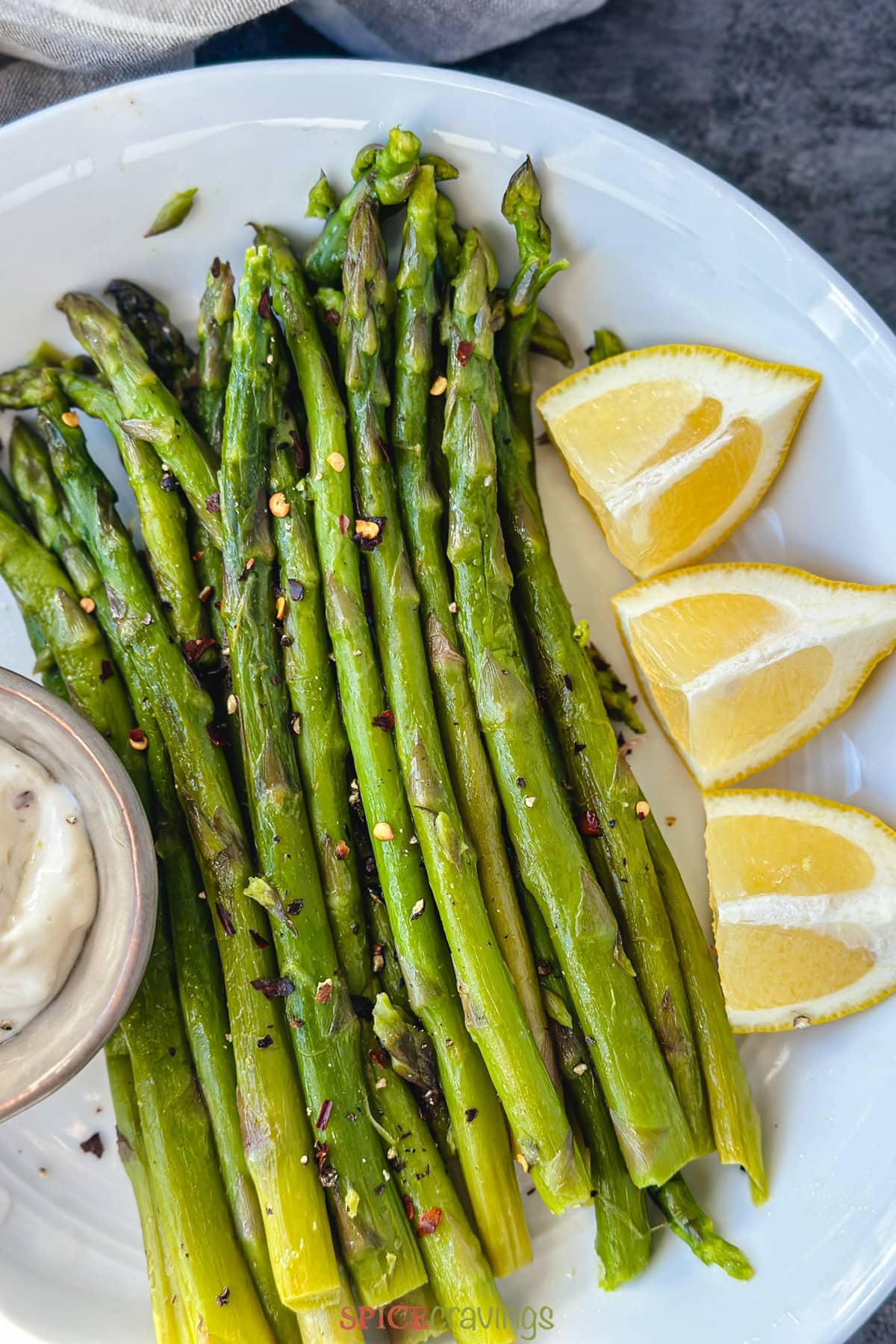 instant pot asparagus with lemon wedges and dipping sauce on white plate