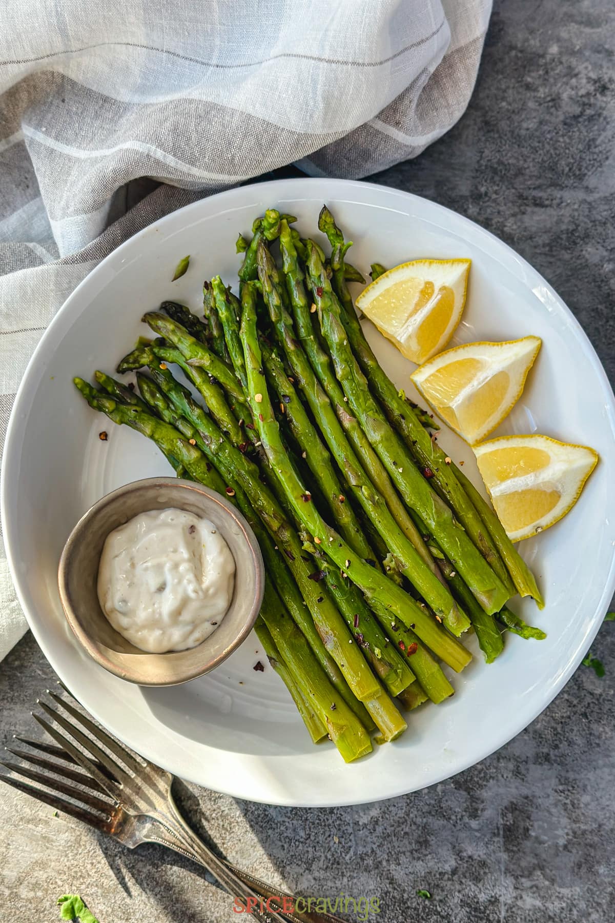 instant pot asparagus spears with lemon wedges and dipping sauce on white plate