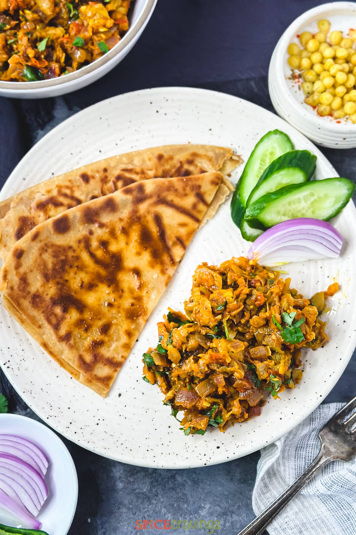paratha with eggplant bharta on plate with cucumber and onion