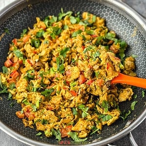Scrambled eggs with vegetables and cilantro in skillet