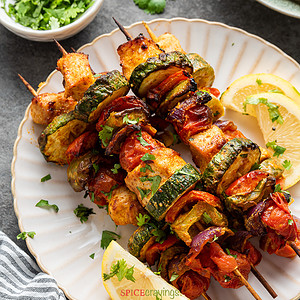 skewers of chicken and vegetables on white plate
