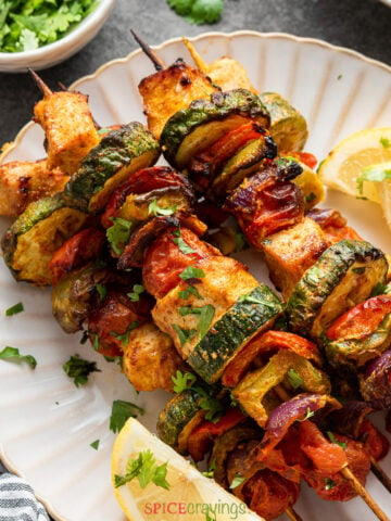 skewers of chicken and vegetables on white plate