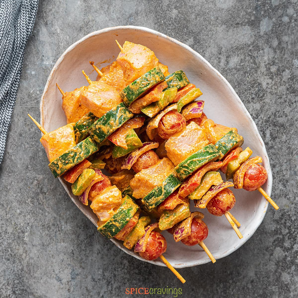 skewers of chicken and vegetables assembled on white plate