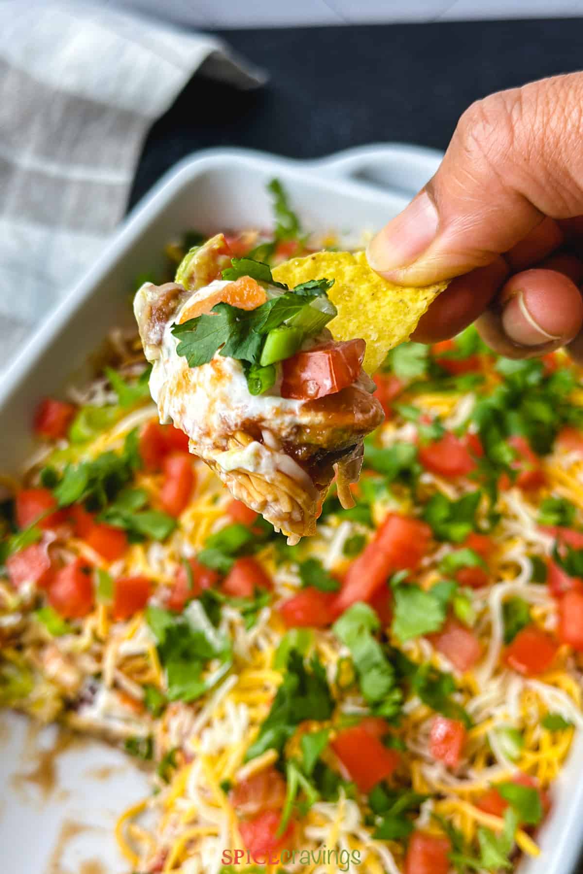 Tortilla chip loaded with layered Mexican dip with beans, tomato, sour cream