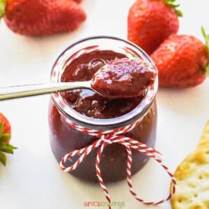 A spoonful of strawberry jam placed over a glass jar
