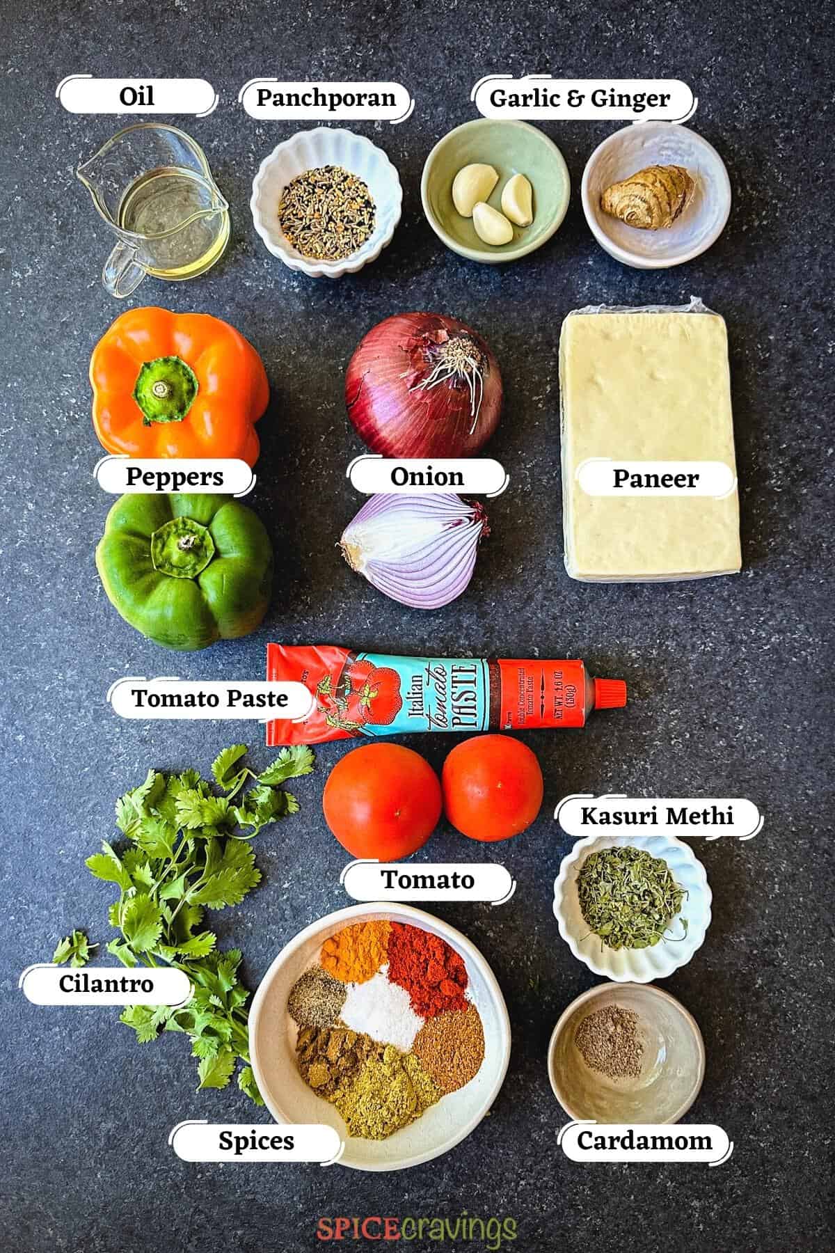 Paneer, peppers and spices among other ingredients on grey board