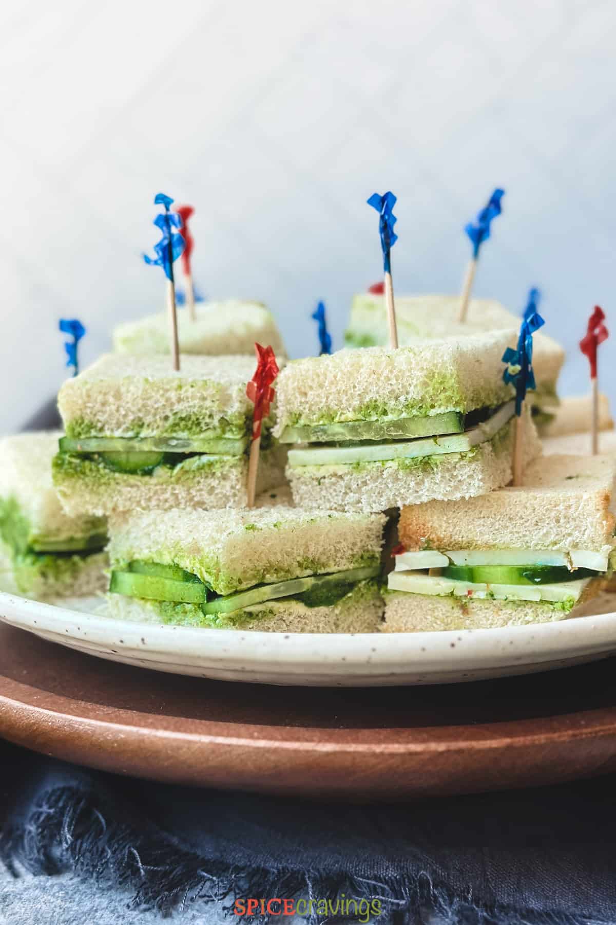 cucumber chutney sandwich squares with toothpicks stacked on a plate