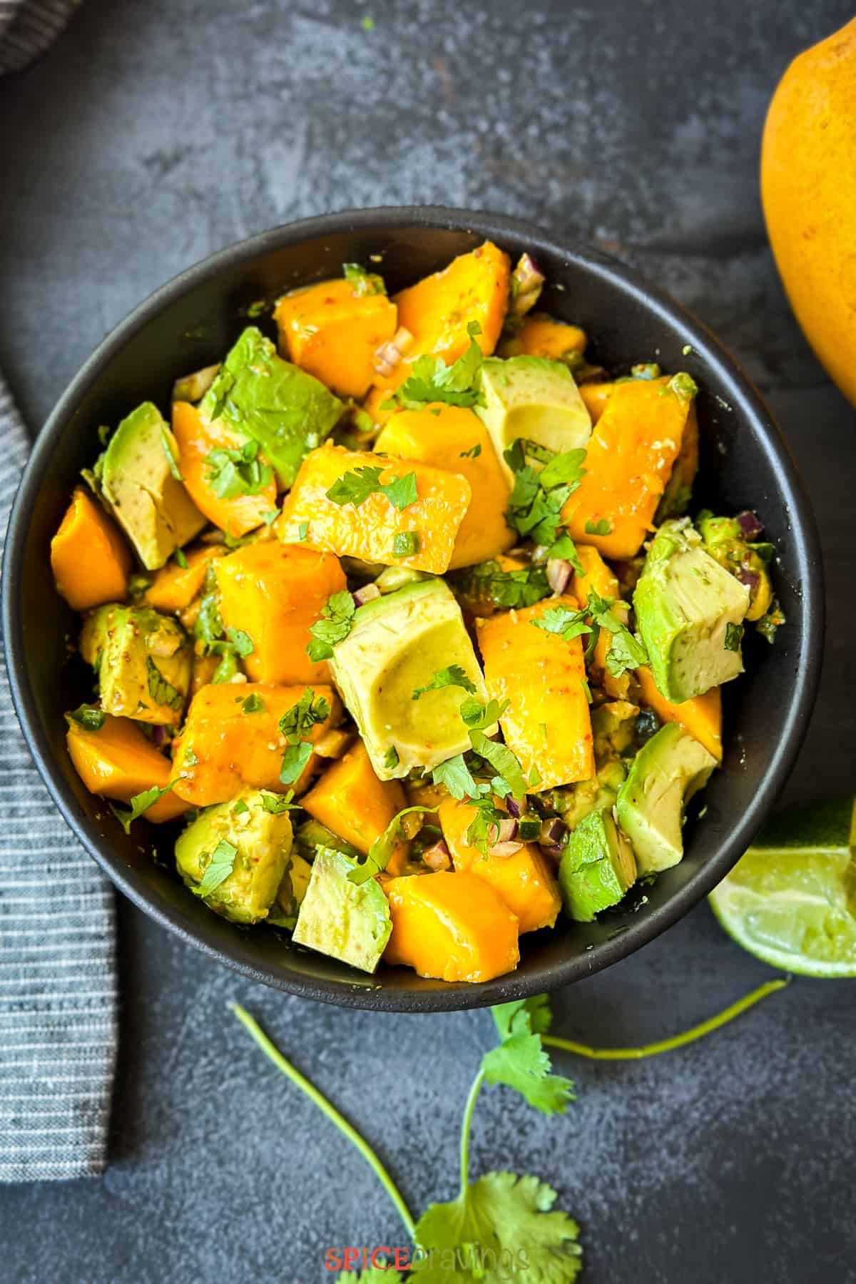 Avocado and mango chunks in bowl garnished with cilantro