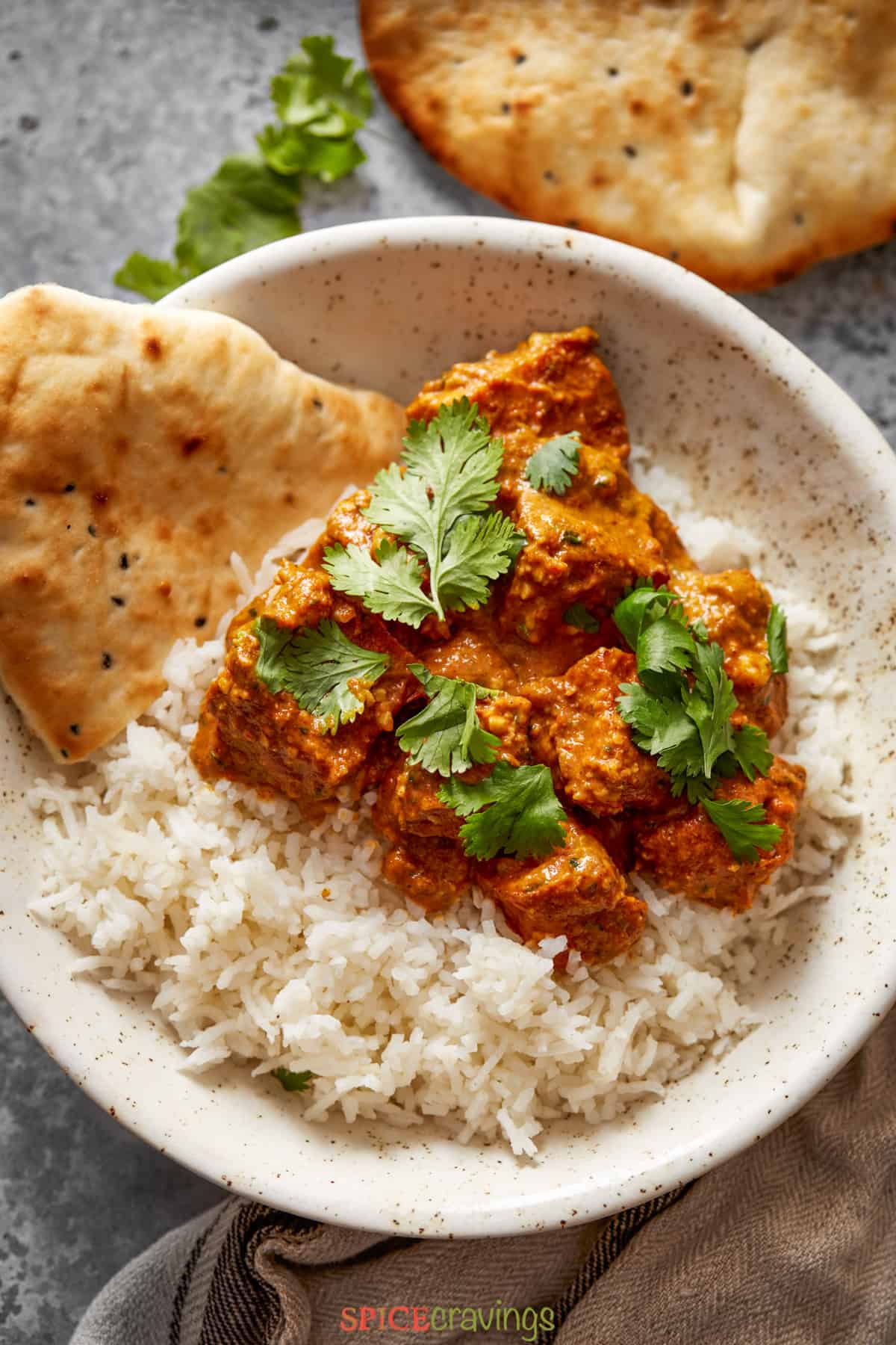tofu tikka masala over basmati rice with naan in white speckled bowl